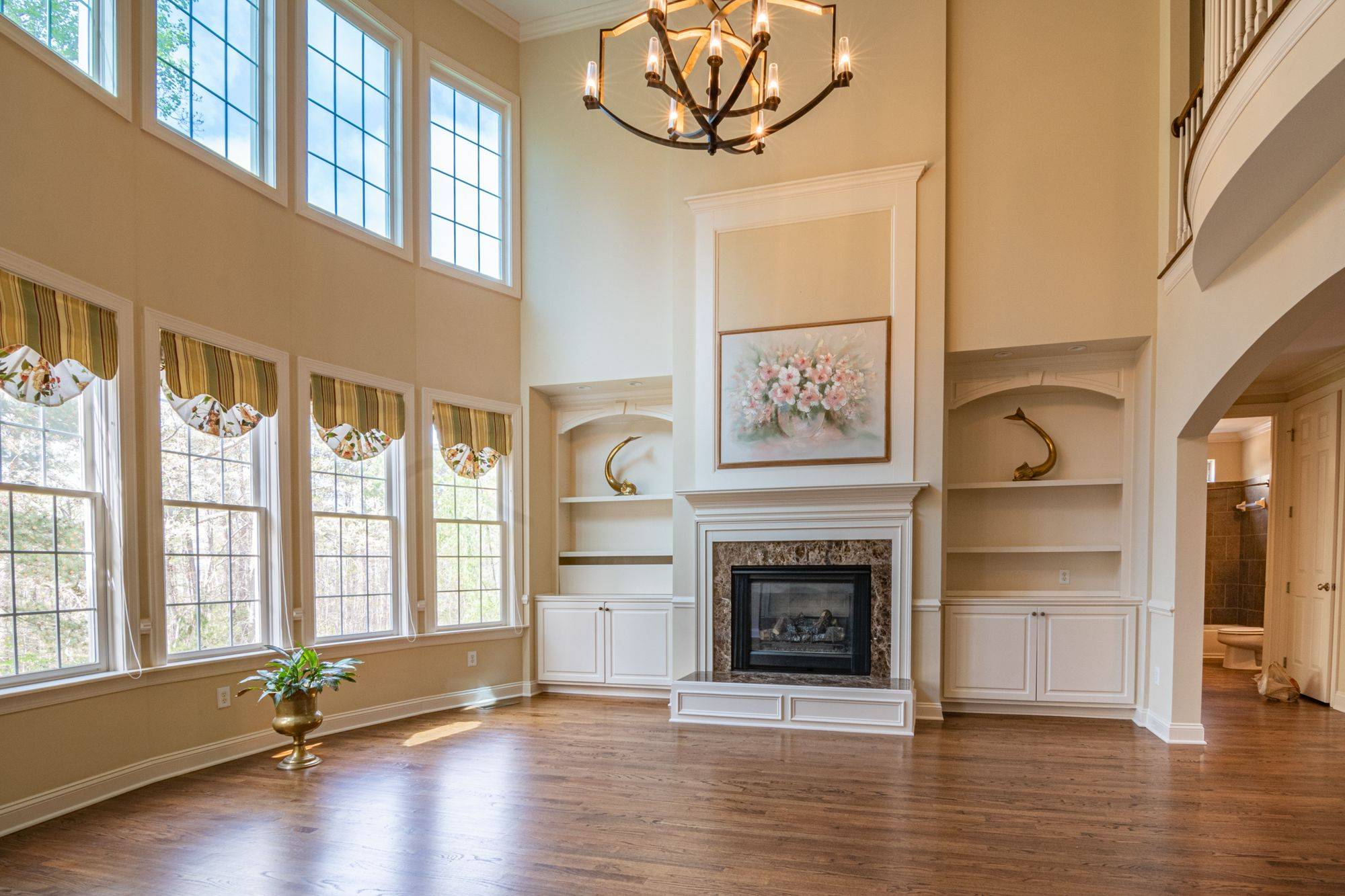 Empty two-story room with tall windows, millwork and fireplace